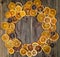 Dry slices of orange on broom wooden background arrange in circle, top view