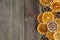 Dry slices of orange on broom wooden background, top view