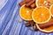 Dry slices of orange, cinnamon, allspice and cardamom on a blue wooden background