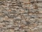 Dry stone wall made of thin horizontal rocks. Colors are shades of brown and gray.