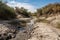 dry streambed with water running downstream, representing the florid past of drought