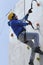 Dry tooling, training. Man in sportswear climbs on a wall using an ice axe