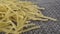 Dry uncooked raw yellow intgral thin vermicelli on a gray plastic wicker mat.