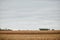 Dry wheat stubble and distant farm machinery