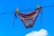 Drying female swimsuit hanging on rope against blue sky