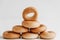 Drying or mini round bagels in the shape of a pyramid on a white wooden background. Copy, empty space for text