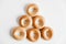Drying or mini round bagels in the shape of a pyramid on a white wooden background. Top view. Copy, empty space for text