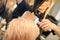 Drying straight blond hair with black hairdryer and white round brush in hairdresser salon, close up.