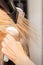 Drying straight blond hair with black hairdryer and white round brush in hairdresser salon, close up.