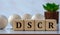 DSCR - acronym on wooden cubes against the background of light balls and cactus