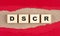 DSCR word on wooden cubes on red torn paper , financial concept background