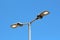 Dual modern LED street lights with adjustable angle mounted on single tall metal pole