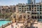 The Dubai fountain lake in the day. Tourists walking on bridge to souk al bahar