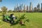 Dubai, UAE - January 12, 2019: Lawn mowing tractor on a green field in front of the skyscrapers of Dubai Marina