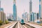 Dubai, UAE, United Arab Emirates - May 28, 2021: Subway train rides among glass skyscrapers in Dubai. Traffic on street