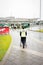 Dublin airport member staff pushing wheelchair for disabled passenger to Terminal building on summer rainy day, Dublin Airport, 14