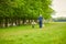 Dublin, Ireland - 05.08.2021: Man with two dogs walking near a herd of wild deer which roam and graze in Phoenix Park, Dublin, Ire