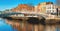 Dublin, panoramic image of Half penny bridge, or Ha`penny bridge, on a bright day with beautiful reflection of historic houses an