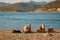 Dubrovnik, Croatia - October 12, 2019: Two young women are laying at the pebble beach with panorama of mountains
