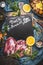 Duck breast on black chalkboard background with oranges and herbs and vegetables ingredients with copy space for text for cooking