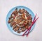 Duck with rice and sesame, Asian recipe, red chopsticks on a blue plate wooden rustic background top view close up