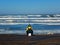 Dude on Ocean Beach in San Francisco doing some surf fishing while sitting on an upside down bucket.