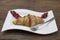 Dukan Diet. Fresh delicious croissant at Dukan Diet on a porcelain plate with a spoon on a wooden background.