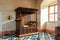 Duke`s room with and coloured glazed clay tiles on the floor and antique wooden child carved tester bed