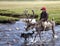 Dukha Boy rides reindeer across river with dog