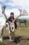 A Dukha boy stands with his reindeer