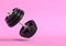 Dumbbell with black plates levitating in air on bright pink background