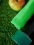 Dumbbell, green towel and an apple on grass. Concept of sports and healthy lifestyle.