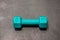 Dumbbell in a silicone shell of turquoise color on the gray floor