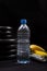 Dumbbell, sports equipment, water bottle, banana on a black background