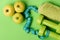Dumbbells in bright green color, twisted measure tape, towel, fruit