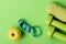 Dumbbells in green color, twisted measure tape, fruit and towel