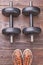 Dumbbells and sneakers, wooden background.