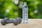 Dumbbells and water bottle side view on aluminium floor on blurred bokeh background