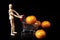 Dummy pushing a shopping cart with tangerines on black background. Symbol of commerce