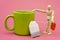 Dummy stands next to ceramic mug and holds teabag