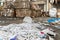 Dump pile of used shreded paper wrap and document against bales of compressed cardboard collected for recycling and