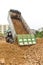 Dump truck dumps its load of rock and soil on land