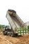 Dump truck dumps its load of rock and soil on land