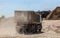 dump truck on a dusty road delivers crushed stone