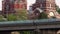 A dump truck rides across a road bridge with a church in the background.