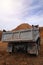 A dump truck unloads sand in the construction site