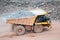 Dumper truck driving in an active quarry mine of porphyry rocks.