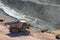 Dumper truck driving around in open pit mine of porphyry rock.