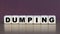 DUMPING - the word on the cubes on a beautiful burgundy background