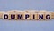 DUMPING - word on wooden cubes on a beautiful gray background